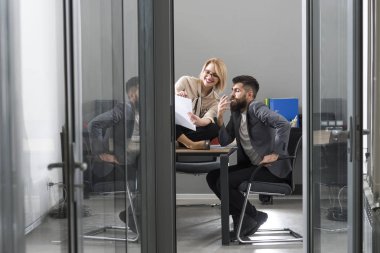 Modern ofisinde çalışan genç meslektaşlarının mutlu çift. İki arkadaşları tartışırken iş, belgelerle çalışma, kağıt üzerinde işaret