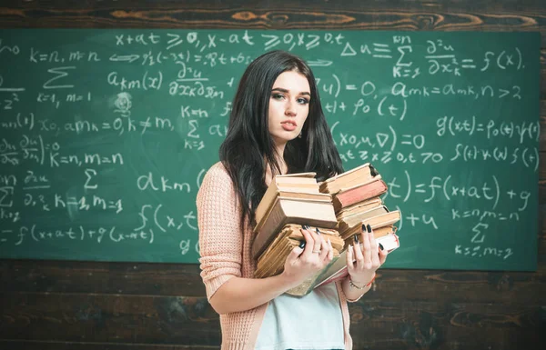 Ze houdt van lezen. Meisje nerd houdt zware stapel van oude boeken, schoolbord achtergrond. Meisje bookworm nemen boeken in bibliotheek. Student uitstekende fond van lezing. Ijverige leerling examen test voorbereiden — Stockfoto