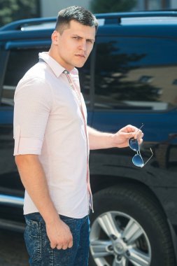 Sürücü hazır yakınındaki şehir sokak araba. Şık giysiler açık güneşli üzerinde iş adamı. Otomobil taşıma adam. Seyahat ve ulaşım kavramı
