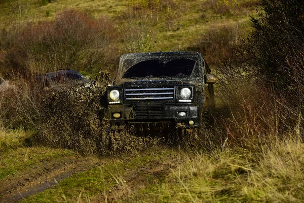 Geländewagen nimmt an Autorennen auf Naturhintergrund teil. Extrem- und Allradantrieb. Schmutzspritzer unter Geländewagen auf Landstraße. Crosslauf im herbstlichen Wald — Stockfoto