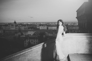 Şehir Manzaralı, moda akşam üzerinde beyaz gelinlik kadın. Şehvetli kadın balkonda, güzellik uzun saçlı. Gelin Makyaj ile. Kız Düğün glamour bakışla.