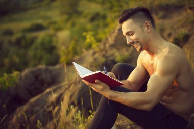 Kitap açık ile gülümseyen kaslı adam