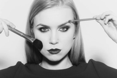 Kadının yüzündeki tozu ve makyaj uygulayarak fırçaları ile