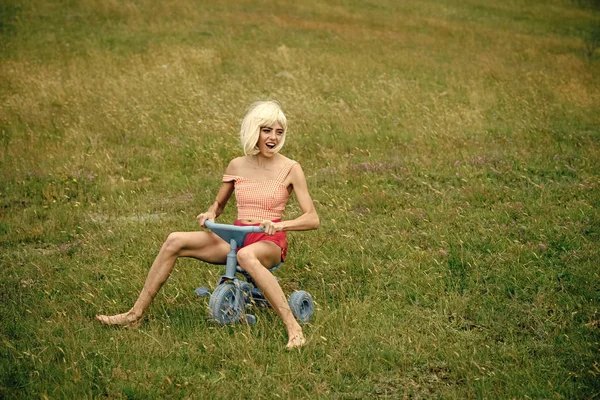 Mulher feliz jogar na bicicleta de brinquedo no verão . — Fotografia de Stock