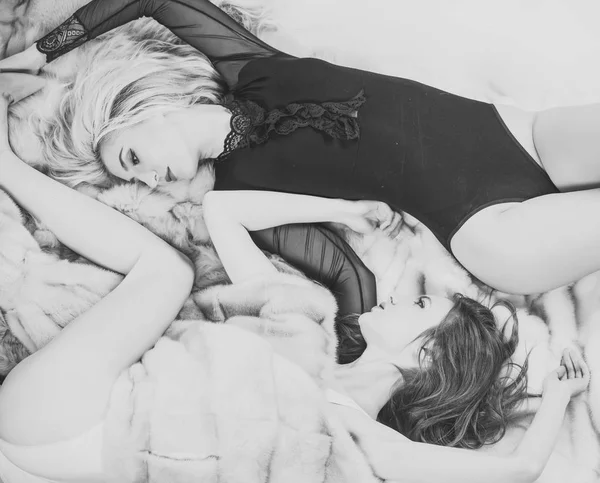 Kobiet z włosami blond i brunetka leżą na futro naturalne — Zdjęcie stockowe