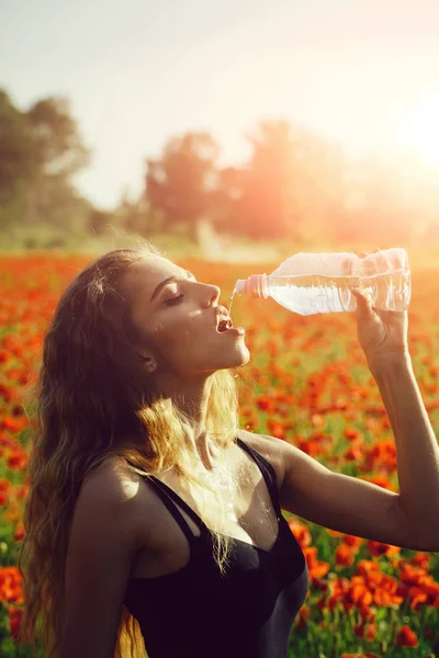 Fille dans le champ de graines de pavot boire de l'eau de la bouteille — Photo