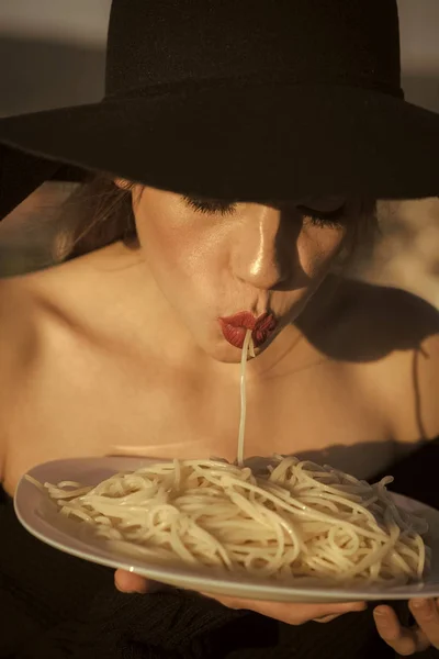 Espaguetis en manos de mujer elegante en sombrero negro. espaguetis como comida tradicional italiana — Foto de Stock