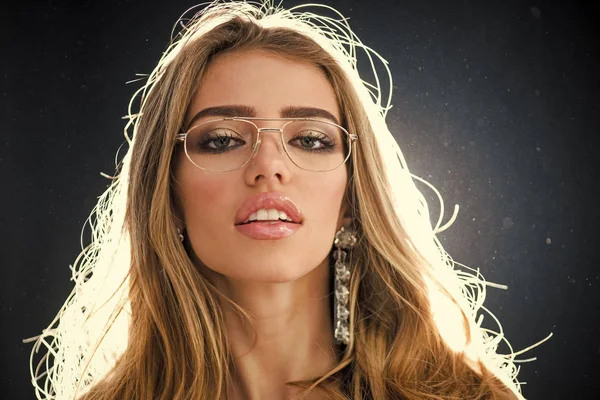 Concept de magasin d'optique. Beauté fille de mode avec maquillage et gros bijoux de boucles d'oreilles, fond studio sombre. Femme aux lèvres sensuelles porte des lunettes métalliques pour la vision. Fille a besoin de lunettes modernes . — Photo