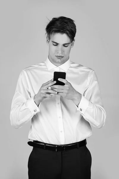 Liikemies valkoisessa paidassa, siniset housut kalvosinnapilla käytä puhelinta — kuvapankkivalokuva