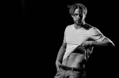 Beyaz tişörtlü yakışıklı adam seksi, kaslı gövdesini gösteriyor.