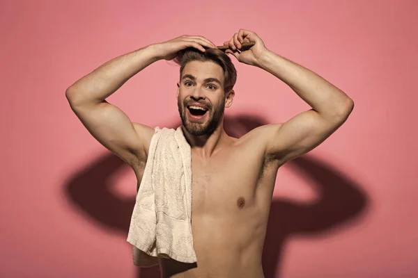 Man brush hair with hairbrush on pink background