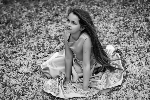 Little girl on green grass with petals — Stock Photo, Image