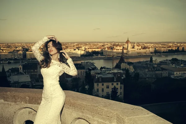 Femme mariée en robe de mariée blanche sur la vue sur la ville. Mariée aux cheveux longs sur le balcon . — Photo