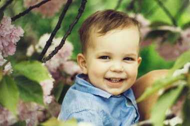 Çiçek çiçekler arasında anne kollarında gülümseyen şirin mutlu çocuk