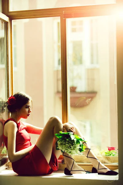 Bela menina espanhola sentada na janela com buquê de flores — Fotografia de Stock