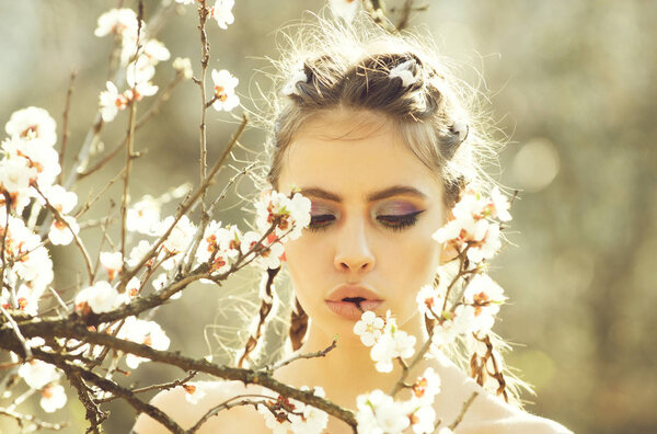 Girl in white cherry or apricot spring flower blooming. pretty woman with fashionable make up on face and stylish hair sunny outdoor on natural background