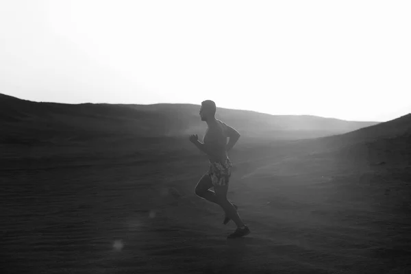 Man runner running in dune at sunset