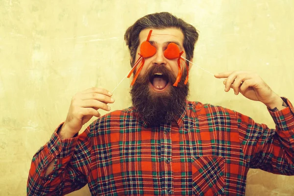 Счастливый бородатый мужчина держит красные сердца на палочках перед глазами — стоковое фото
