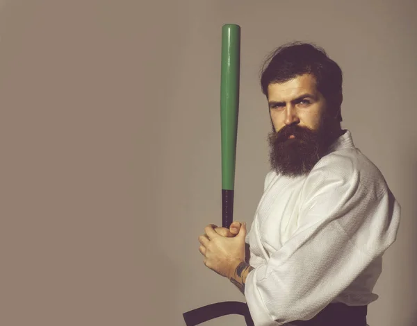 Bearded serious karate man in kimono with green baseball bat — Stock Photo, Image