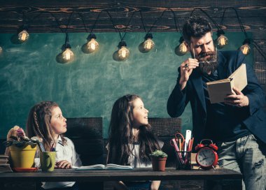 Öğretmen ve kız öğrencilerin sınıfta, kara tahta arka plan. Öğretmen dikkat ile dinleme meraklı çocuk. Sakallı adam kız öğrenciler, kitap okuma öğretir. İlköğretim Okulu kavramı.