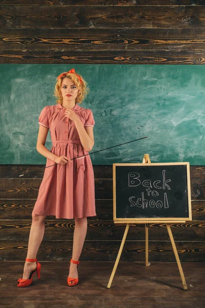 Woman is back to school. Pretty woman in vintage dress with pointer at classroom blackboard. Adorable and genius — Stock Photo, Image