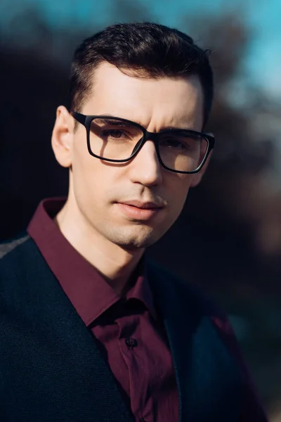 Close up Jovem empresário vestindo óculos, olhando para a câmera contra o fundo natural . — Fotografia de Stock
