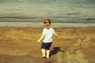 Şirin bebek çocuk kum ile kumlu plaj üzerinde çalış.