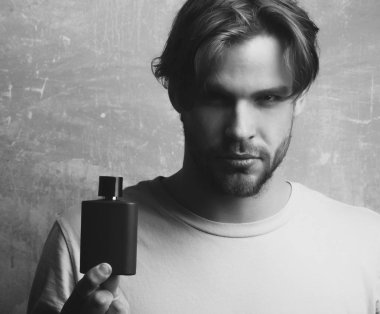 Yakışıklı adam siyah parfüm şişesi ile poz