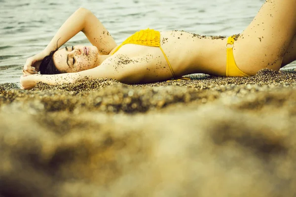 Hübsches Mädchen im gelben Badeanzug schläft am Strand — Stockfoto