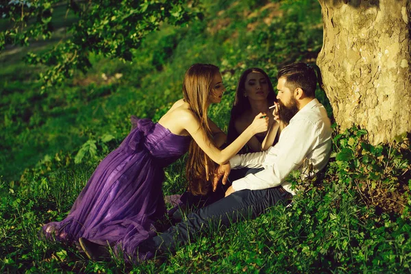 Бородатый мужчина и две женщины на траве — стоковое фото