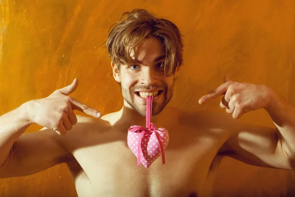 Bebaarde gespierde man met sexy lichaam houdt pink valentines hart — Stockfoto
