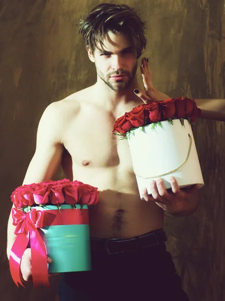 bearded muscular man with sexy body holds red rose box