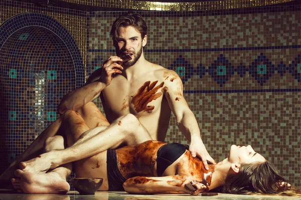 Gespierde man en sexy vrouw eten chocolade na de massage salon — Stockfoto