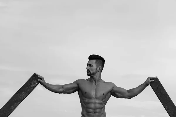 Mann mit muskulösem Körpertraining an rostiger Eisenstange — Stockfoto