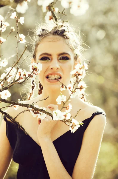Girl in teeth braces eating white cherry spring flower blooming — Stock Photo, Image