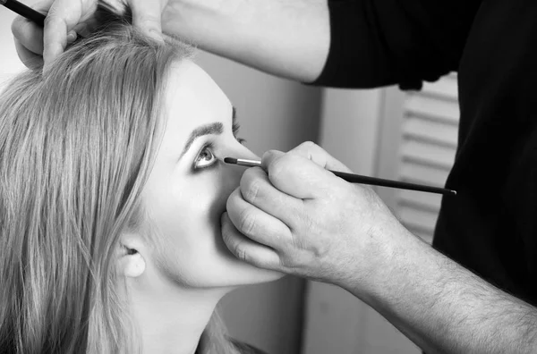 Visagiste aplicar maquillaje de ojos en la cara de chica con cepillo — Foto de Stock