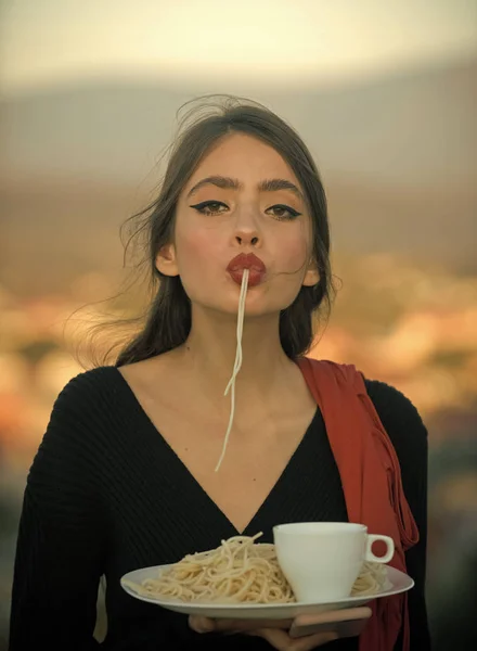 Szef kuchni kobieta z czerwonymi ustami jeść makaron i napić się kawy. Szef kuchni, smaczne breacfast lub kolację z makaronu i herbata — Zdjęcie stockowe
