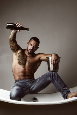Şampanya ya da şarap kutlaması. Şarap festivali konsepti. Dövmeli, yakışıklı bir adam. Gri arka planda yakışıklı, vahşi bir adam. Çıplak vücutlu Mude erkek modeli.