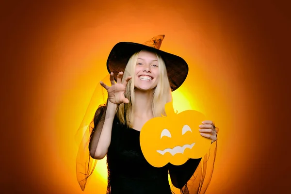 Holiday halloween with funny carnival costumes on halloween background. Background decorated for Halloween. Sexy young woman Witch hat. Halloween Witch with carved Pumpkin, magic lights in dark forest