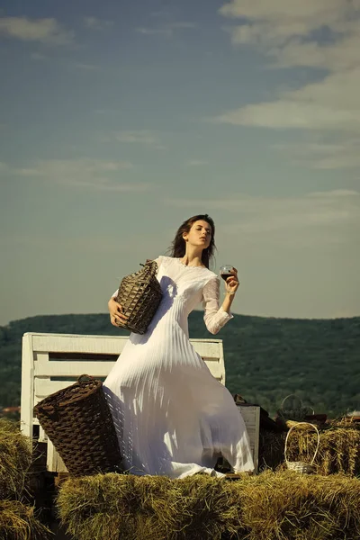 Kobieta z kieliszek wina, butelka wiklinowe i kosz — Zdjęcie stockowe