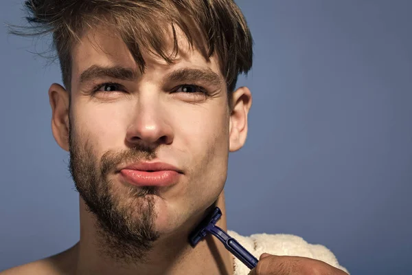 Ungkarl raka hälften skäggiga ansikte med rakblad på blå bakgrund — Stockfoto