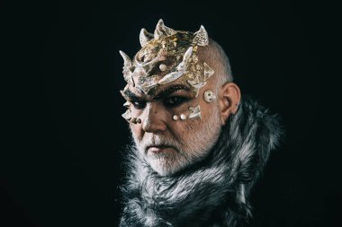 Uzaylı, iblis büyücü makyaj. Beyaz sakallı komuta sizde canavar gibi giyinmiş. Siyah arka plan, kopya alanı cehennemdeki şeytanlar. Dikenler veya siğiller kürk paltolu adam. Tiyatro makyaj kavramı.