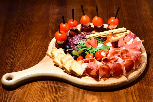 Plateau de charcuterie. Plateau en bois avec charcuterie et canape. Une oasis de plaisir — Photo