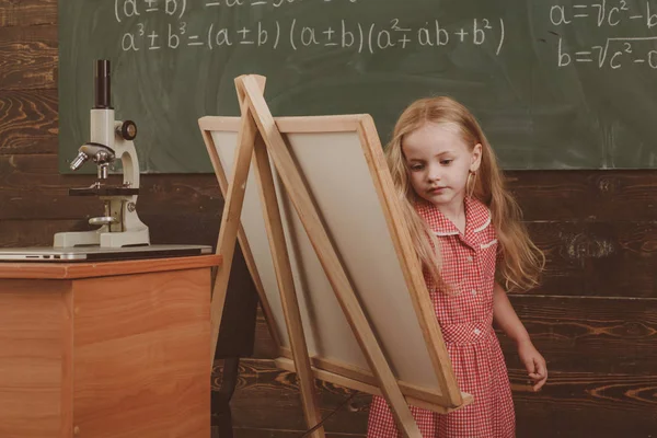 Carino ragazza artista pittura quadro su tela su cavalletto. Bambino imparare a disegnare su cavalletto studio, filtro vintage — Foto Stock