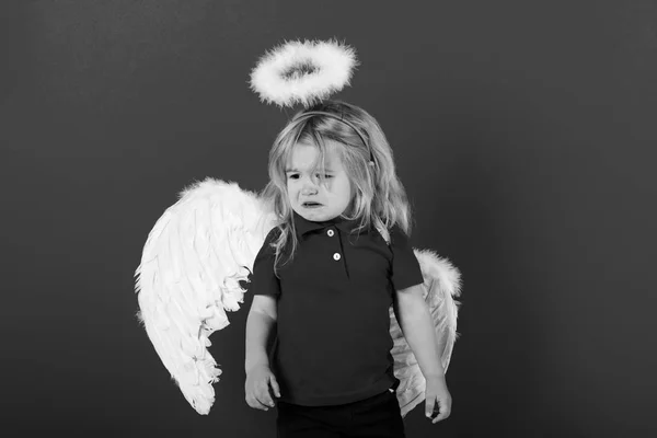 Menino anjo chorando com asas de penas brancas e halo — Fotografia de Stock