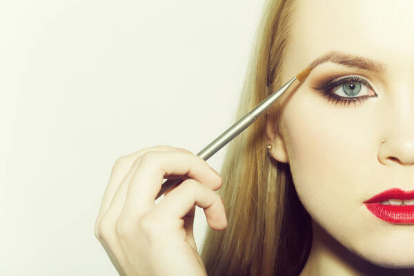 Woman applying eyeshadow on eye with makeup brush