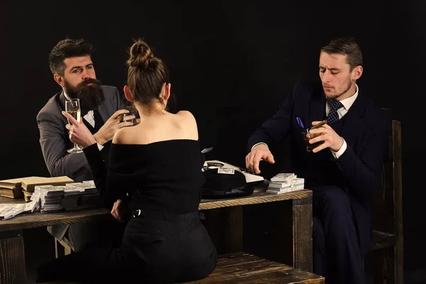 Men and woman sitting at table with piles of money. Illegal deal concept. Businessmen discussing illegal deal while drinking and smoking, dark interior background. Company engaged in illegal business.