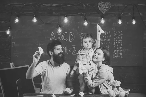 American family at desk with son play with paper planes. Homeschooling concept. Kid with parents in classroom with usa flag, chalkboard on background. Parents teaching son american traditions playing. — Stock Photo, Image