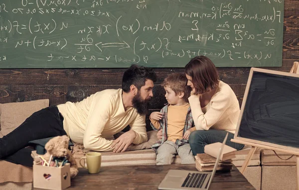 Homeschooling concept. Parents teaching kid, speaking. Boy listening to mom and dad with attention. Parents teaches son, chalkboard on background. Family cares about education of their son. — Stock Photo, Image