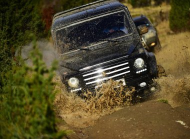 Otomatik Sonbahar Doğa arka plan üzerinde yarış. Rekabet, enerji ve motor sporları konsept. Sonbahar ormanda yarış araba. Yol araç veya Suv geçiş su birikintisi kir sıçrama ile
